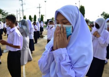 PELAJAR mengaminkan doa ketika perhimpunan sekolah di Narathiwat, selatan Thailand. - AFP