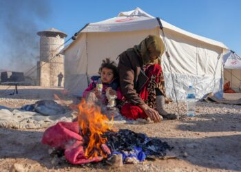 PENDUDUK Syria memanaskan badan dengan api di tempat perlindungan sementara bagi mereka yang kehilangan tempat tinggal, berhampiran bandar Jindayris,  Syria.-AFP