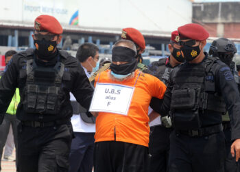 ANGGOTA polis mengawal ketat seorang suspek pengganas di Lapangan Terbang Antarabangsa Soekarno-Hatta, Tangerang. -AFP