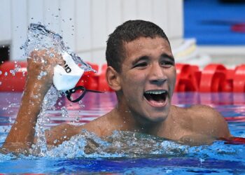 PERENANG remaja Tunisia, Ahmed Hafnaoui meraikan kejayaan apabila memenangi pingat emas Olimpik dalam acara 400m gaya bebas di Pusat Akuatik Tokyo.- AFP