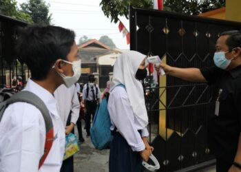 PETUGAS memeriksa suhu badan pelajar di Jakarta. - AFP