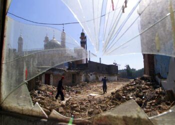 DUA penduduk etnik Uighur berjalan melintasi runtuhan bangunan berdekatan masjid di wilayah Xinjiang. - AFP