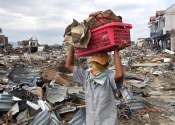 Seorang peniaga membawa keluar barangan dari kedainya di Banda Aceh pada 31 Disember 2004 yang musnah dihentam tsunami. – afp