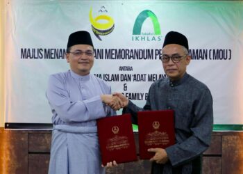 MUHAMMAD Fikri Mohamad Rawi (kiri) dan Shahrul Azam Shaari bertukar dokumen kerjasama selepas majlis menandatangai MOU antara Takaful IKHLAS dan MAIPk di Ipoh, Perak.