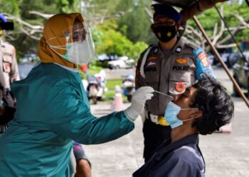 PETUGAS kesihatan melakukan ujian saringan Covid-19 terhadap seorang penduduk di Aceh pada Julai lalu. - AFP