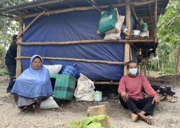 NGADIONO bersama isterinya di hadapan kandang lembu yang menjadi tempat keluarganya tinggal di Gunungkidul, Yogyakarta, Indonesia. - AGENSI