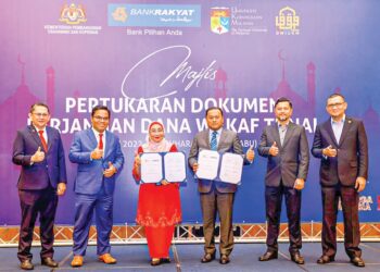 DR.Norazah Mohd. Nordin dan Abdul Razak Abu Bakar (tiga, kanan) menunjukkan dokumen memorandum perjanjian yang ditandatangani di Menara Kembar Bank Rakyat, Kuala Lumpur.