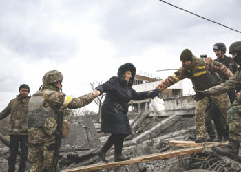 SEORANG wanita dibantu oleh tentera Ukraine semasa menyeberangi jambatan yang musnah dibedil untuk melarikan diri ke bandar Irpin, barat laut Kyiv. - AFP