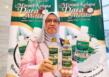 JUNAIDAH Ibrahim menunjukkan produk Minyak Kelapa Dara Melaka pada Program Turun Padang Ke Arah Memasyarakatkan Koperasi 2023 di sebuah hotel di Banda Hilir, Melaka. – UTUSAN/MUHAMMAD SHAHIZAM TAZALI