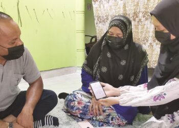 NUR Aisyah Zakaria menunjukkan keputusan SPM kepada Siti Hawa Ahmad dan Zakaria Ahmad di Kampung Teluk Nibong, Langkawi, Kedah, semalam. - UTUSAN/NUR AMALINA AZMAN