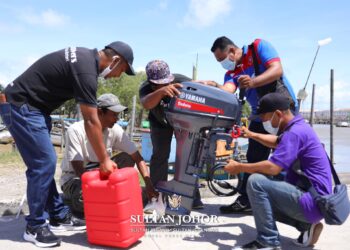 HAZLAN Harun (kanan) bersama-sama rakan nelayan melihat enjin  motor yang dikurniakan oleh   Sultan Ibrahim Sultan Iskandar baru-baru ini.