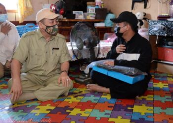 HAJIJI Noor (tengah) beramah mesra dengan pelajar SMK Kudat, Muhd Azman selepas menyampaikan bantuan komputer riba di Kampung Landung Ayang, Kudat, Sabah hari ini.