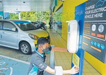 SEORANG pekerja stesen minyak Petronas memeriksa kemudahan pengecas EV yang disediakan di stesen itu. – GAMBAR HIASAN