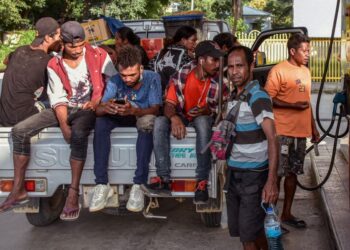 PENDUDUK Timor Leste duduk di belakang sebuah lori sambil mengisi minyak di stesen minyak swasta di Dili.-AFP