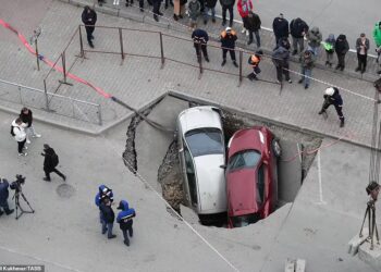 KEADAAN dua kenderaan yang terbenam dalam lubang di jalan raya di Novosibirsk, Rusia.-TASS