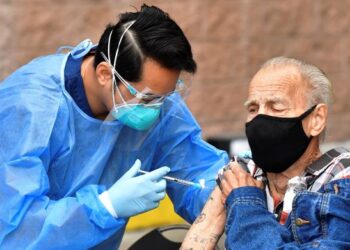 SEORANG warga emas menerima suntikan vaksin Covid-19 di sebuah pusat vaksinasi di kawasan kejiranan Skid Row, Los Angeles. – AFP