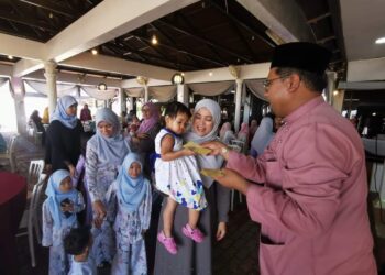 MOHD. Ishak Abdillah Ngah (kanan) menyampaikan duit raya kepada kanak-kanak yang hadir pada majlis sambutan Hari Raya Aidilfitri di Kuala Terengganu, baru-baru ini. – UTUSAN/KAMALIZA KAMARUDDIN