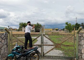 SEORANG lelaski sanggup berdiri di atas motosikal untuk merakam gambar Istana Raja Muda Perak dari luar pagar di Teluk Intan, Perak.-UTUSAN/AIN SAFRE BIDIN