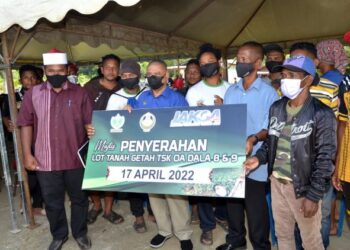 SAARANI Mohamad (tengah) menyaksikan penyerahan cek pada program penyerahan ladang TSK RPS Dala 8 dan Dala 9 di Gerik hari ini. - UTUSAN/ZULFACHRI ZULKIFLI