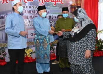 HAJIJI Noor (dua kiri) menyampaikan sumbangan kepada salah seorang penerima di Masjid Wasatiyyah, Sandakan semalam.