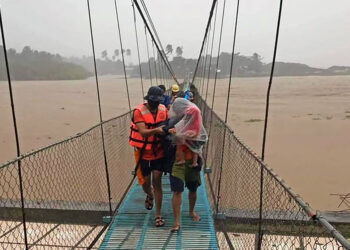 PASUKAN penyelamat membantu penduduk berpindah semasa merentasi sungai di pekan Tubang, selatan Mindanao.-AFP