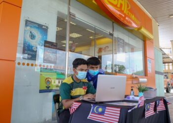 Muhammad Arissyafiq Mohamad Arishan (kiri) dan Luqman Hakim Mad Isa terpaksa menggunakan kemudahan internet di stesen minyak untuk mengikuti kelas dalam talian di Kampung Barokhas, Kuala Nerang, Terengganu, baru-baru ini. – UTUSAN/Shahir Noordin