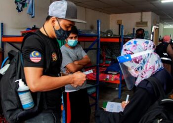 Anggota penguat kuasa Jabatan Tenaga Kerja meneliti dokumen seorang pekerja warga asing dalam operasi, baru-baru ini. – GAMBAR HIASAN/MUHAMMAD IZZAT TERMIZIE