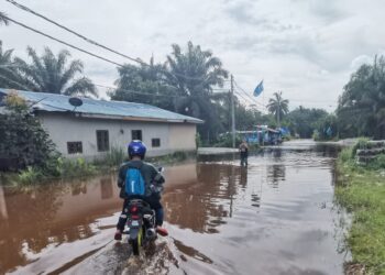 PENDUDUK meredah banjir untuk keluar masuk ke kampung mereka di Batu 7, Jalan Changkat Jong di Teluk Intan, semalam. – UTUSAN/AIN SAFRE BIDIN