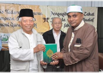 MOHD. Yusof Noor (kiri) menyampaikan senaskhah al-Quran kepada saudara baharu ketika majlis tadarus al-Quran dan pengagihan wang zakat di surau Pertubuhan Kebajikan Islam Malaysia (Perkim) di Jalan Sultan Azlan Shah, Kuala Lumpur.