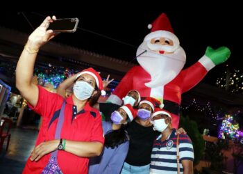 S. SUGUNA (depan) tidak melepaskan peluang merakam gambar kenangan di hadapan hiasan rumah penduduk sempena Hari Krismas di Perkampungan Portugis, Ujong Pasir, Melaka. UTUSAN/ RASUL AZLI SAMAD