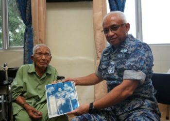 FOTO kenangan Allahyarham Ujang Mormin (kiri) menunjukkan gambar lama kepada Panglima Angkatan Tentera, Jeneral Tan Sri Affendi Buang dalam satu majlis sebelum ini.