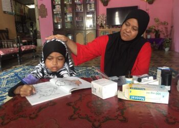 NUR Suhadah Mohd. Pellee (kiri) mewarna buku lukisan sambil diperhatikan oleh ibunya di Kampung Bukit Perah, Pasir Mas, Kelantan. – UTUSAN/ROSMIZAN RESDI