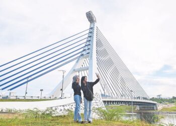 DUA pengunjung mengambil kesempatan berswafoto di jambatan ikonik Pulau Poh, Tasik Kenyir, Hulu Terengganu. - UTUSAN/PUQTRA HAIRRY ROSLI