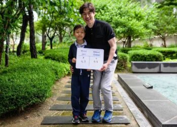 SEORANG penduduk bersama anaknya memegang papan putih yang menunjukkan usia antarabangsa mereka di Yoon Dong-gun di Seoul. - AFP  