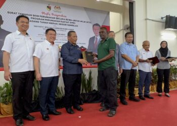 AMINUDDIN Harun (tiga dari kiri) bersama Nga Kor Ming (dua dari kiri) menyerahkan surat tawaran pada Majlis Penyerahan Surat Tawaran Skim Perumahan Rakyat (PPR) Ladang Tanah Merah di Port Dickson hari ini.-UTUSAN/ZAKKINA WATI AHMAD TARMIZI.