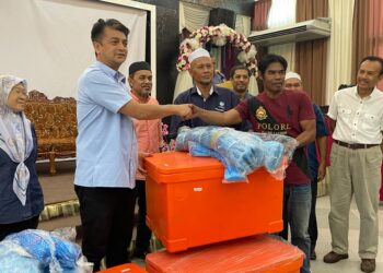 MUHAMMAD Faiz Fadzil (dua kiri) ketika mengagihkan bantuan kepada nelayan PNK Bachok, di D'Haritage Resort and Training Center, Bachok, Kelantan hari ini. UTUSAN/TOREK SULONG