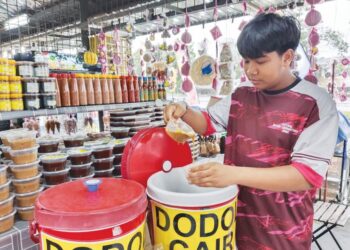 MUHAMMAD Fakhruddin Norankhairolhidzam mengisi dodol cair ke dalam bekas untuk dijual kepada pelanggan di gerainya di Simpang Ampat, Melaka.