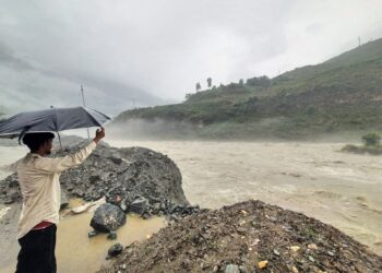 SEORANG penduduk memegang payung sambil berdiri di tebing sungai Satluj selepas hujan lebat melanda Rampur di Himachal Pradesh.