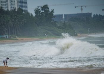 PENDUDUK menyaksikan ombak besar di tepi pantai sebelum Taufan Talim membadai di Boao, wilayah Hainan, selatan China. - AFP