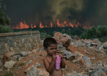 SEORANG kanak-kanak minum air selepas diselamatkan daripada kebakaran hutan berhampiran perkampungan Agios Charalampos di Athens, Greece.-AFP