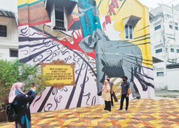 PELANCONG bergambar di salah satu lorong yang mempunyai lukisan mural di Teluk Intan, Perak. - UTUSAN/AIN SAFRE BIDIN