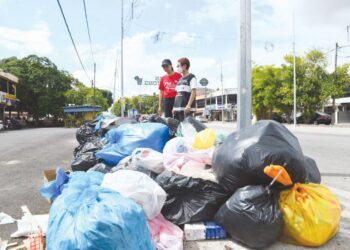 YAP Beng Ean (kanan) dan Gan Ay Ling meninjau keadaan longgokan sampah yang dibuang di tepi jalan sehingga mengundangkan pencemaran bau di Persiaran Makanan Bintong, Kangar, Perlis. - MINGGUAN/IZLIZAN OTHMAN