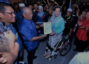 MUHYIDDIN Yassin menyerahkan watikah keahlian Bersatu kepada Ras Adiba pada Majlis Pelancaran Jentera Pilihan Raya PN Negeri Sembilan di Seremban malam ini.-UTUSAN/MOHD. SHAHJEHAN MAAMIN.