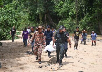 ANGGOTA pasukan operasi mencari dan menyelamat mengusung mayat salah seorang mangsa tragedi kepala air yang ditemukan di Air Putih, Kemaman, semalam.  - UTUSAN/PUQTRA HAIRRY ROSLI