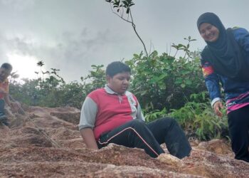 DUA pelajar PPKI dibantu juruiring semasa mendaki Gunung Semanggol, Bagan Serai, Perak, semalam. - UTUSAN/WAT KAMAL ABAS