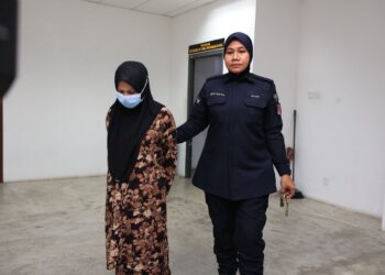 TERTUDUH (kiri) diiringi oleh anggota polis semasa menghadiri perbicaraan di Mahkamah Tinggi Kota Bharu, Kelantan.-UTUSAN/KAMARUL BISMI KAMARUZAMAN