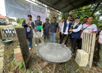 NORAZIAN Awang (kiri) mengacau bubur asyura bersama penduduk Kampung Seneng, Bachok, Kelantan. - UTUSAN/TOREK SULONG