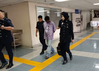 K. Letchumanan diiringi polis tiba di Mahkamah Majistret Ampang bagi menghadapi pertuduhan menipu seorang pesara lelaki warga emas. -  UTUSAN/NORLIZAH ABAS