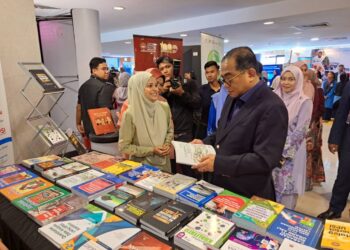 MOHAMED Khaled Nordin diberikan penerangan mengenai buku yang dipamerkan oleh Pejabat Karang Mengarang UPSI ketika lawatan kerja ke universiti itu di Tanjung Malim hari ini. - UTUSAN