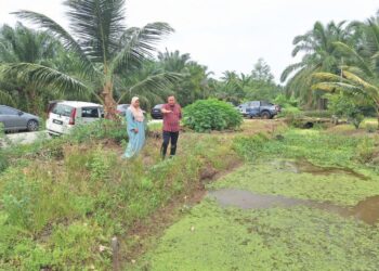 RIZAM Ismail dan Sawiah Dolah Sadari melihat parit yang mengakibatkan limpahan banjir di Kampung Batu 38 Baroh, Sabak Bernam, Selangor. - UTUSAN / ISKANDAR SHAH MOHAMED